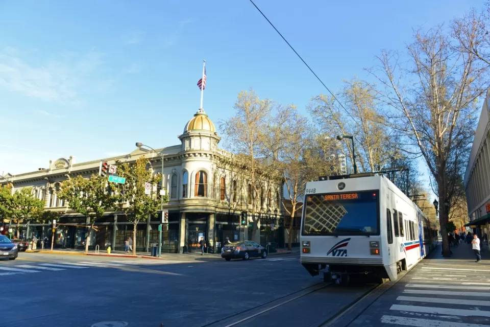 White VTA light rail train passing by historic building in downtown San Jose, California